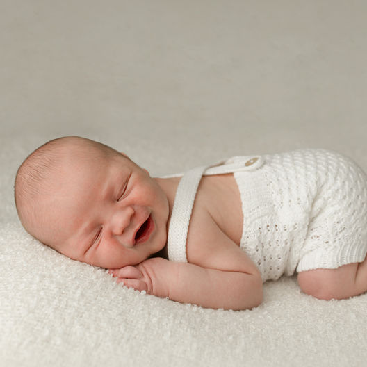 A sleeping newborn baby on a white plain blanket