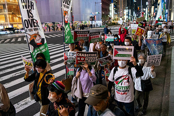 People holding placards and Palestinian flags march though the Intersection at Ginza, one