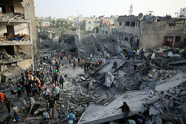 Palestinians search through the rubble of a collapsed building searching for survivors and