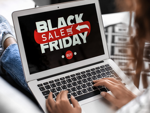 Person types on a laptop displaying "Black Friday Sale" with a red arrow and "Buy" button. Casual seating, cozy ambiance.