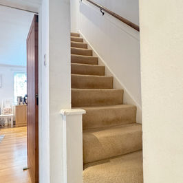 Staircase with white banister and neutral tones leading upstairs.