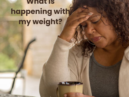 Woman over 50 sitting at a table holding a coffee mug, resting her hand on her forehead, appearing concerned about weight changes