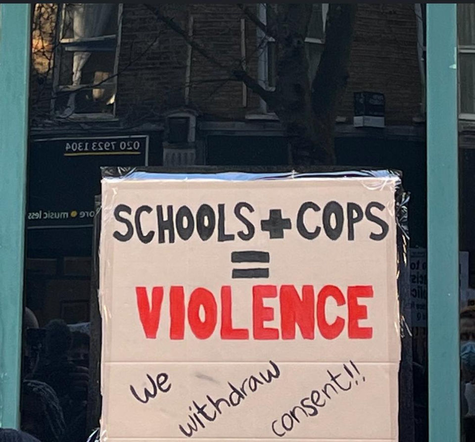 Placard taped to window. It reads: Schools + Cops = violence. Below it reads: We withdraw consent!!