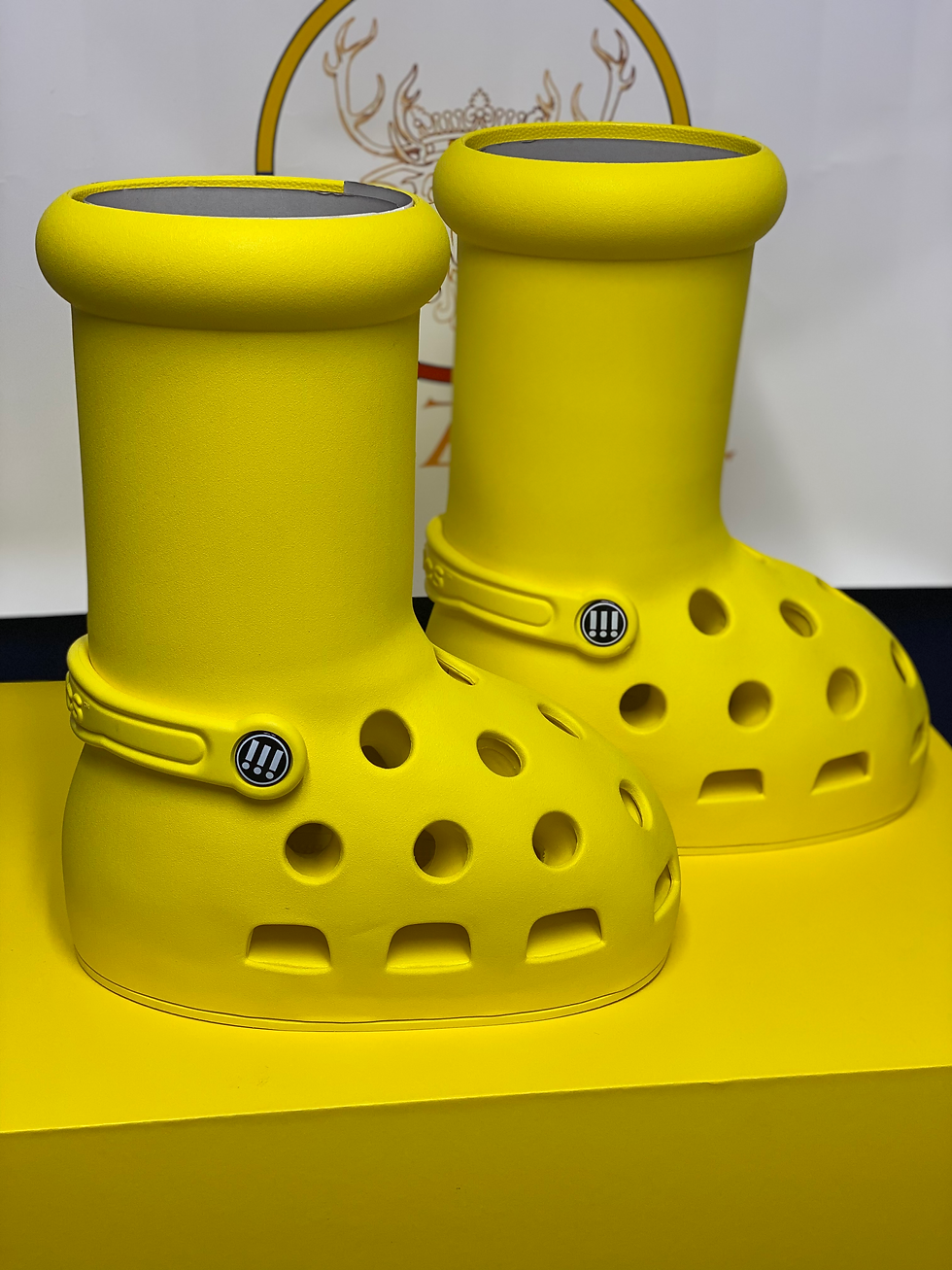 Miniatura: Two bright yellow Crocs-style boots displayed on a yellow platform.