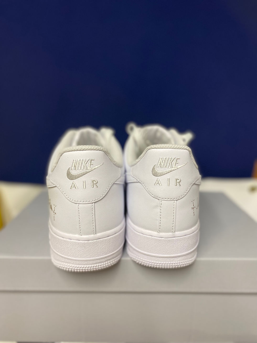 Thumbnail: Two white Nike Air Force 1 "NIKE AIR" sneakers, seen from behind.