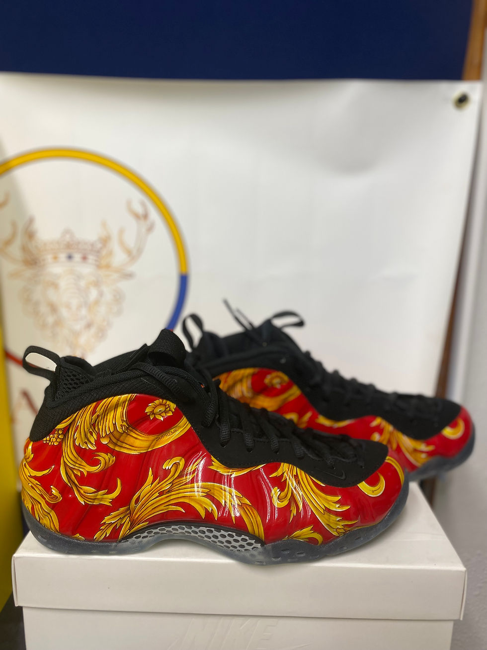 Thumbnail: Pair of red and gold ornate patterned sneakers on a white surface.