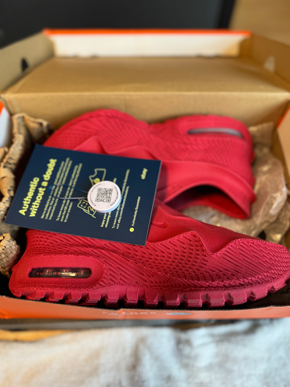 Miniatura: Bright red sneakers in brown box with "Authentic without a doubt" tag.