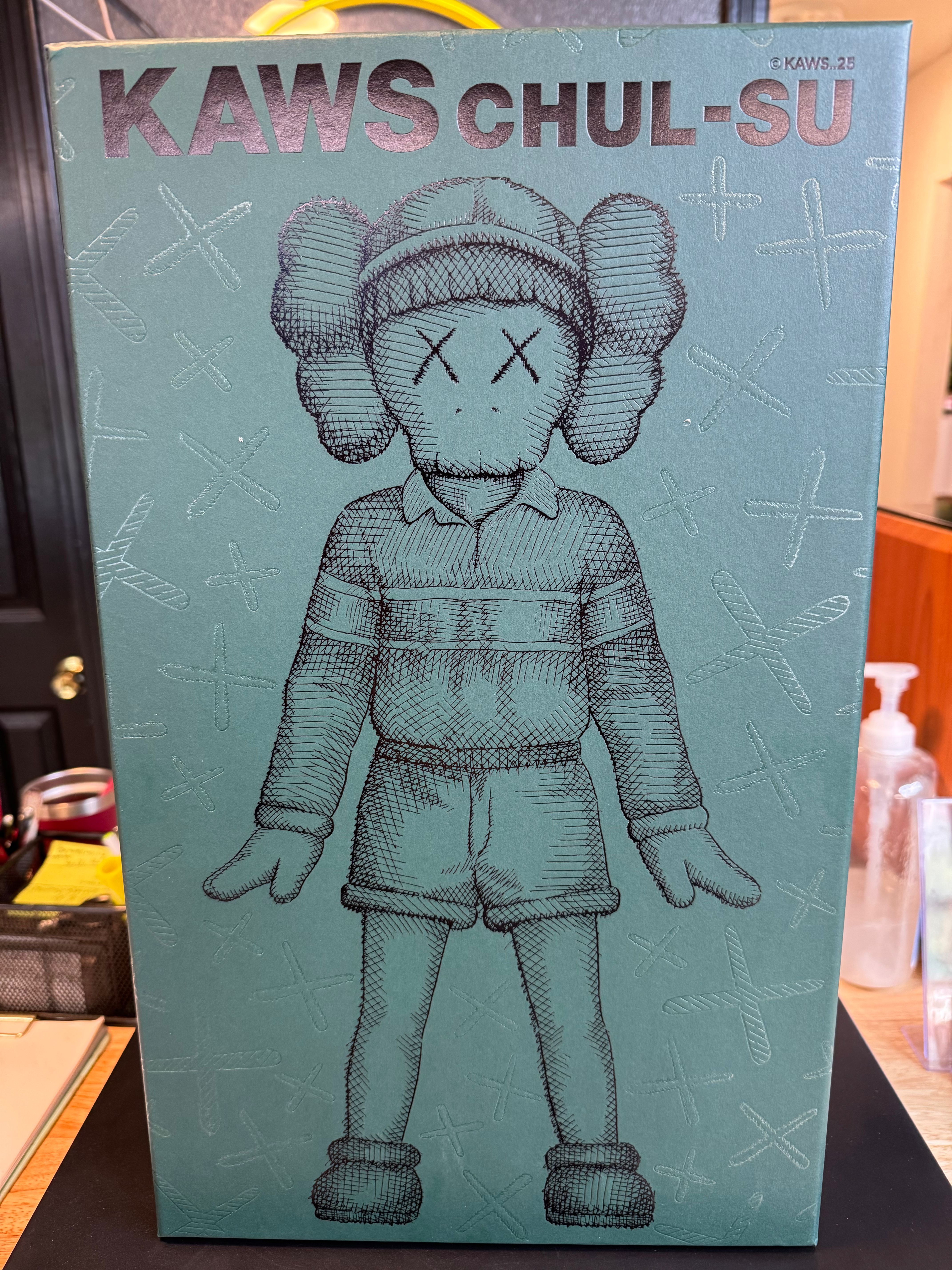 Kaws figure illustration with X eyes on teal blue product box.