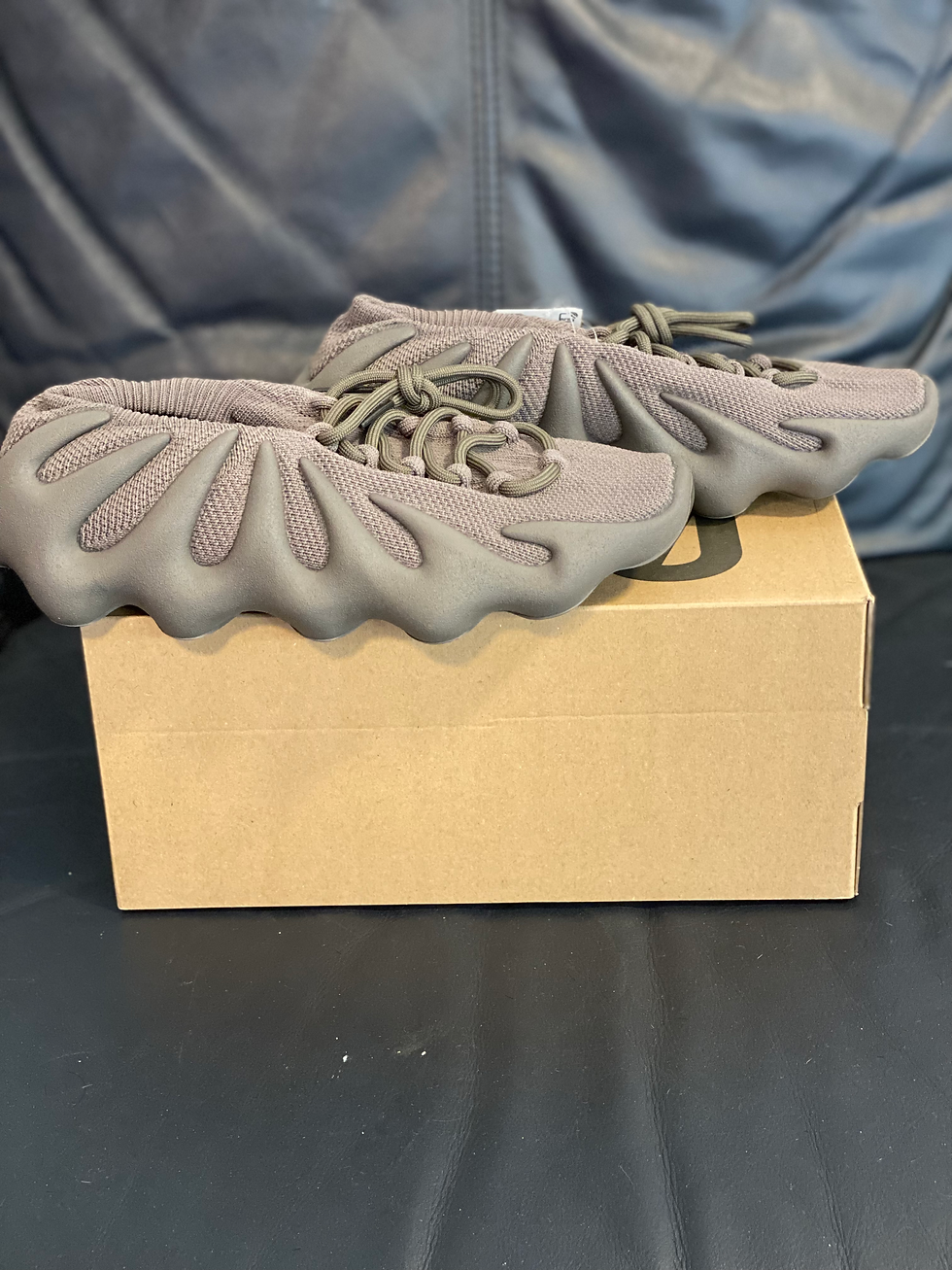Brown Yeezy 450 sneakers with unique sole on a cardboard box.