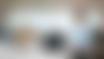 A woman in a blue shirt stands beside a table with a laptop showing data, boxes labeled "ThinkGrid," and devices in a bright office.