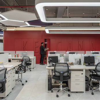 Red cabinetry, perforated ceiling, and custom light pendants in an industrial office