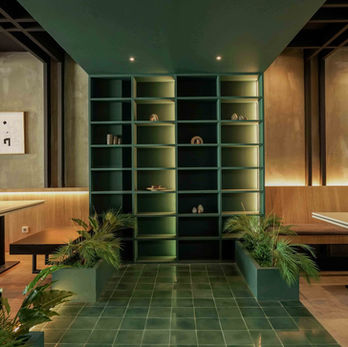 The combination of green cabinet, ceiling, and mosaic tile, with wood panels across the wall in a Cafe