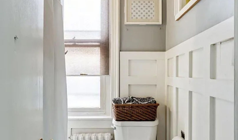 Bathroom with white toilet, wainscoting, and hexagonal tile floor