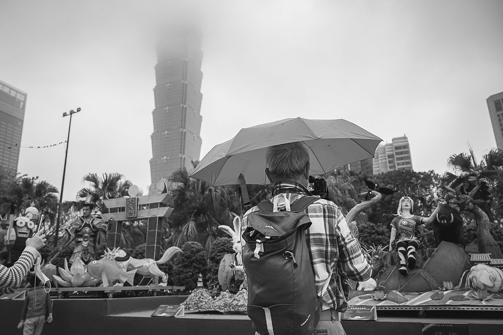 Man with umbrella taking photograph of Taipei 101 in Taiwan