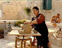 A photograph of Leah on her rooftop in the Jewish Quarter, working on a clay sculpture of a woman. Below the image is a link to a 1986 27-minute documentary about Leah by director Eitan Wetzler. This English version of the film was widely broadcast by television channels and screened by Israeli diplomatic missions worldwide.