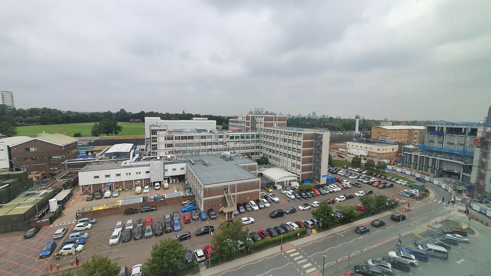 a view of a busy carpark from a 6th storey window, surrounded by buildings