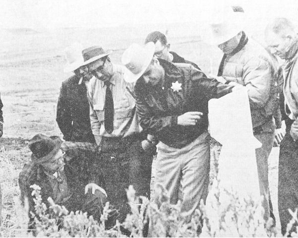 seven men, police officers, man lifting a sheet, four men in hats, police sherif, mckenzie county police, men in glasses and hats