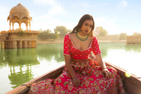 Bride sitting in a boat wearing red bridal lehenga