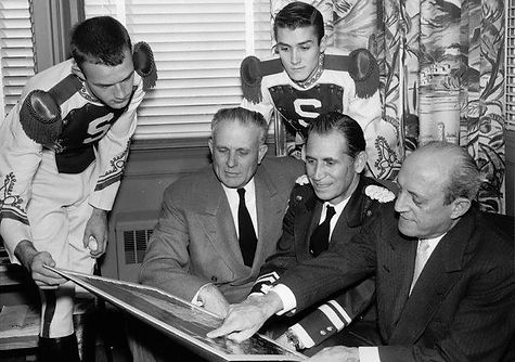 MSU president John Hannah, band director Leonard Falcone, and Oldsmobile general manager Jack Wolfram review Spartan Band charts prior to the 1956 Rose Bowl with drum majors Richard Morsches and Archie Patton looking on, 1955 (Michigan State University Archives and Historical Collections, A001859)