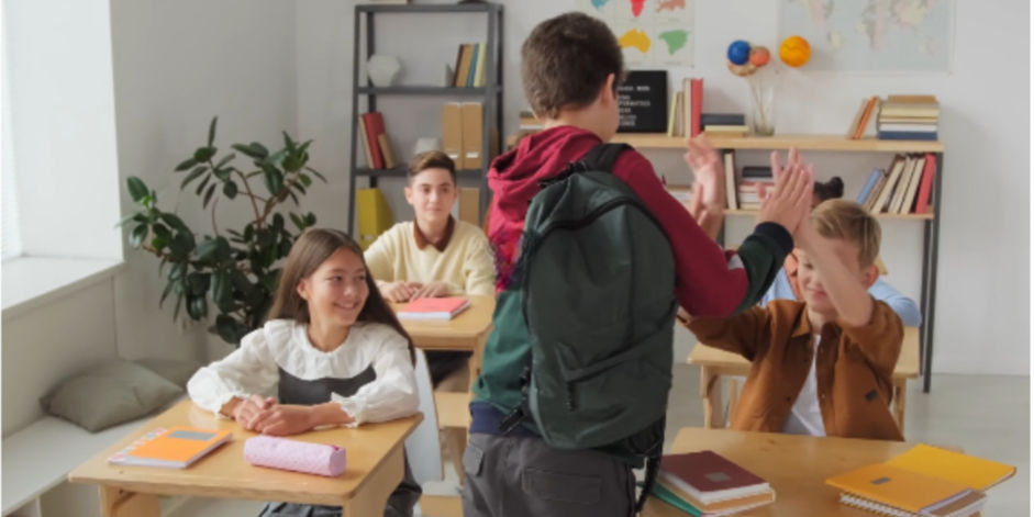 Classmates high-fiving a boy as he walks to his seat on the first day of school.