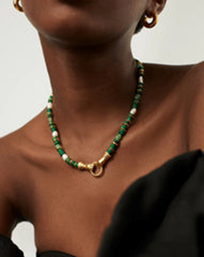 Ragacca di colore che indossa collana di pietre dure verdi, perle e oro