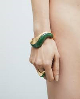 Braccio di donna che indossa un bangle ondulato di giada e oro e un anello dello stesso stile e materiali del bangle, entrambi di Fernando Jorge