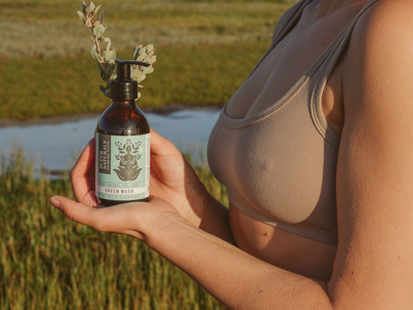 Woman holding SuperNaturals lubricant in fynbos