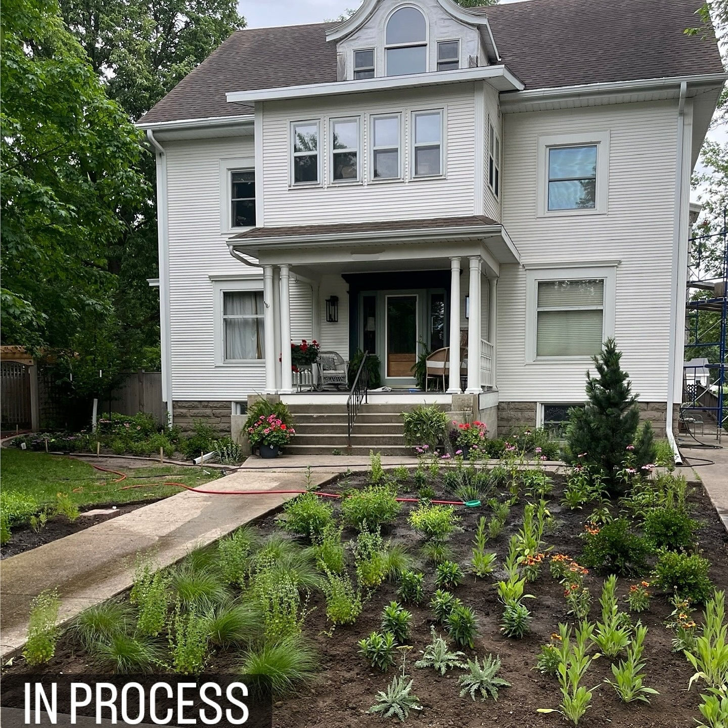 Large white house with garden landscaping in progress.