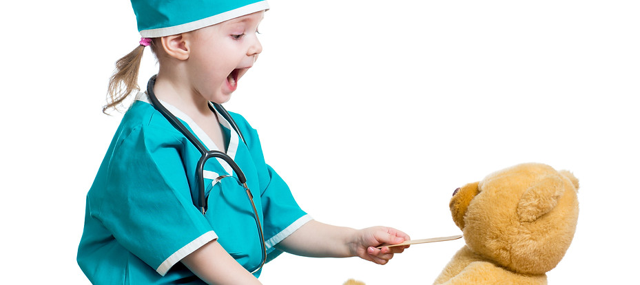 Adorable child dressed as doctor playing with toy over white.jpg