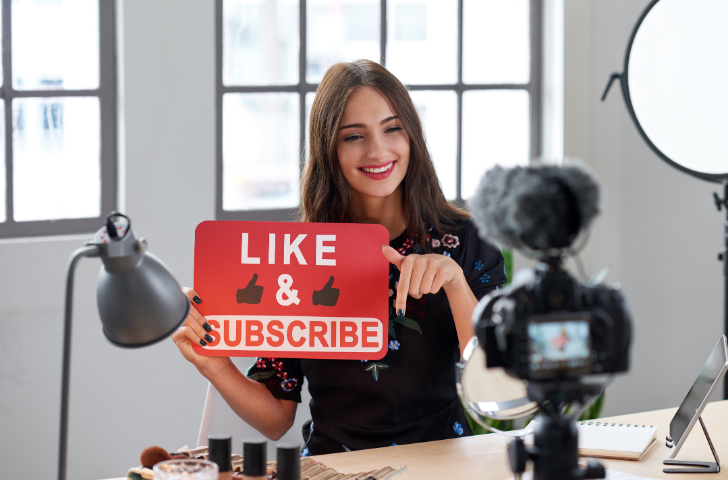 A woman being filmed requesting likes and subscribes