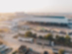 Aerial view of a warehouse yard at sunrise, with parked trucks, loading bays.