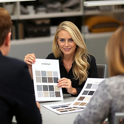 show a woman with blond hair in a black shirt sitting at a table showing another person a