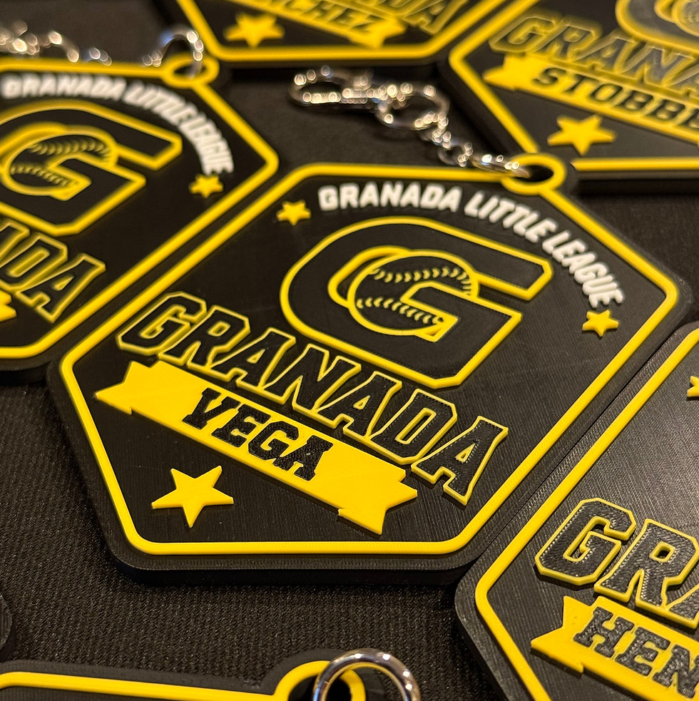 Close-up photo of multiple black and yellow Granada Little League bag tag keychains