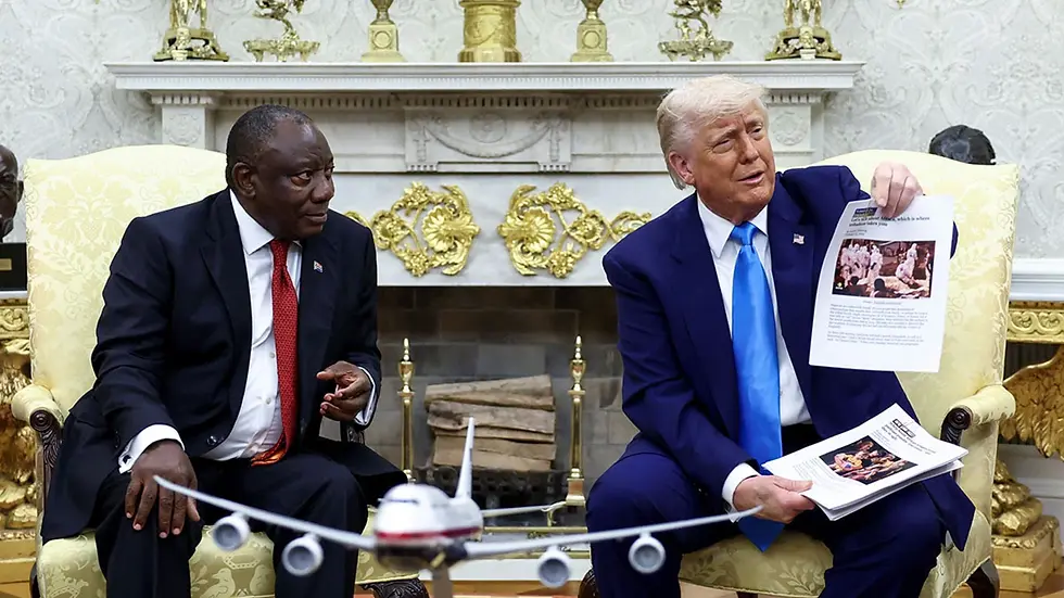 El presidente estadounidense Donald Trump sostiene documentos impresos que contienen presuntas noticias de violencia mientras se reúne con el presidente sudafricano Cyril Ramaphosa en el Despacho Oval (Mayo de 2025).