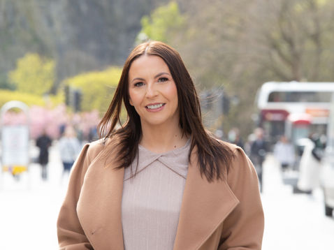 Vicky in a coat standing on a busy street.