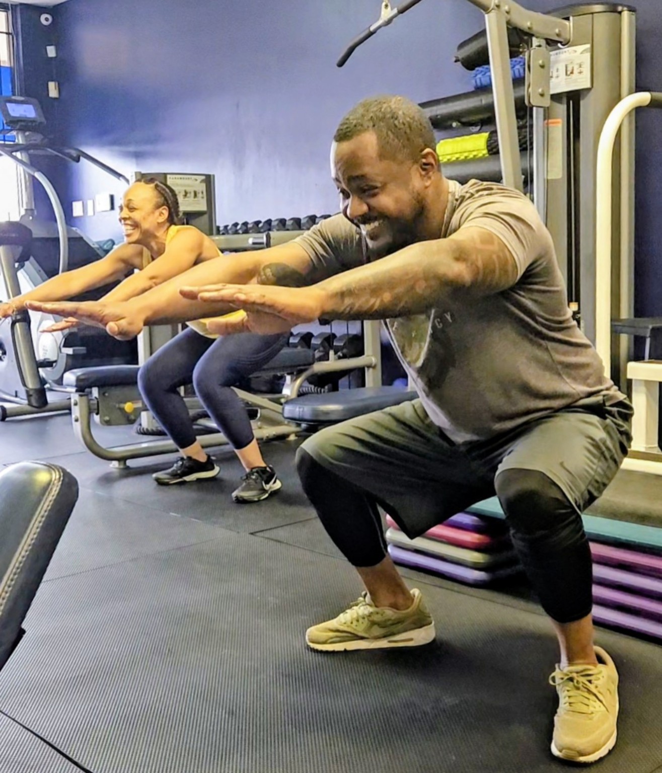 Two Infinite Fitness clients performing squats together during semi-private personal training