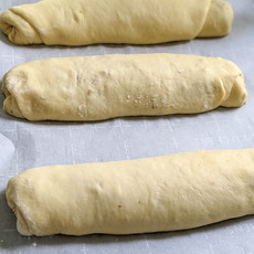 Three completed loaves sit on a parchment lined baking sheet.