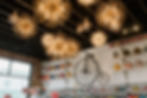 A delightful view inside High Wheel Confectionary, showcasing an array of colorful candies in glass jars, with a vintage bicycle adorning the wall and whimsical chandeliers adding charm to the space.