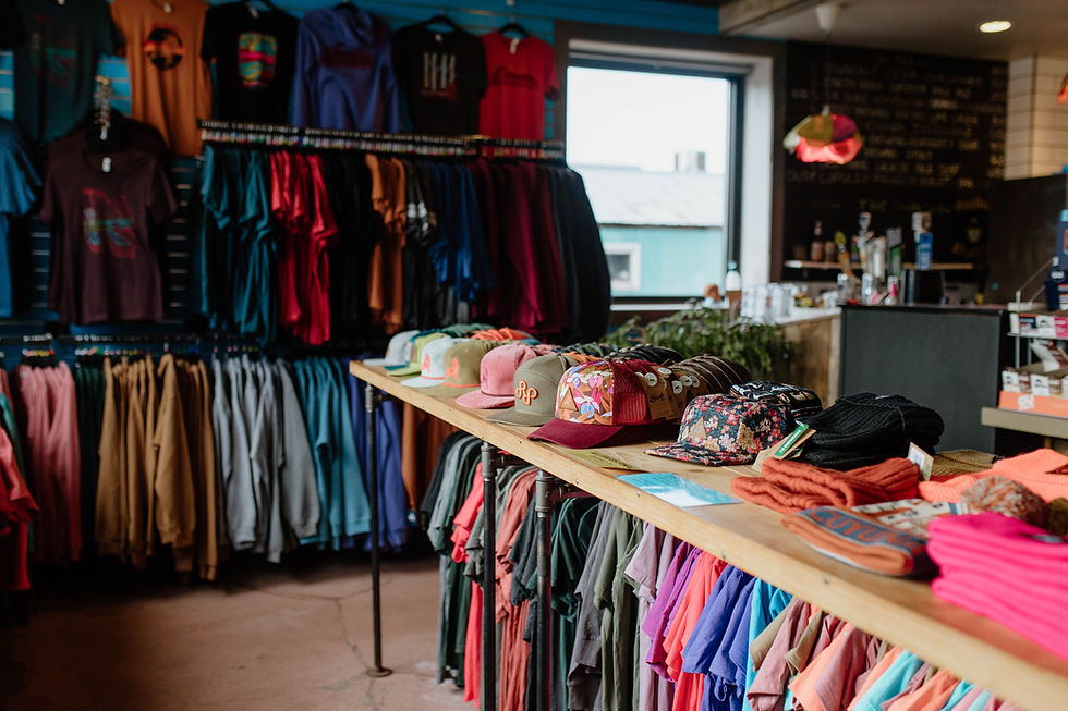 Colorful apparel and hats on display at the Red Raven Bike Cafe's merchandise section, offering a variety of styles for cycling enthusiasts.