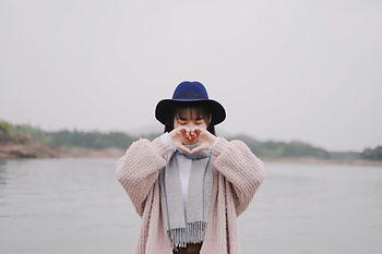A lady looking content making a love heart with her hands