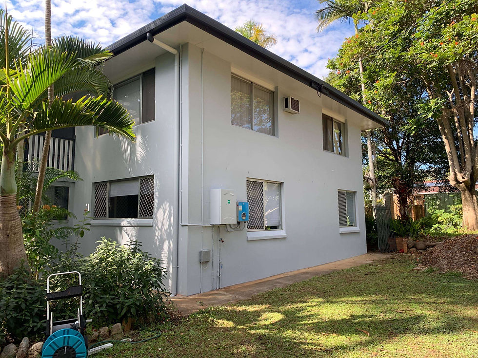 Side exterior of a two-story residential home in Kallangur showcasing a complete facade transformation with smooth cement rendering and a fresh, highly durable protective paint finish by JT Industries & Co.