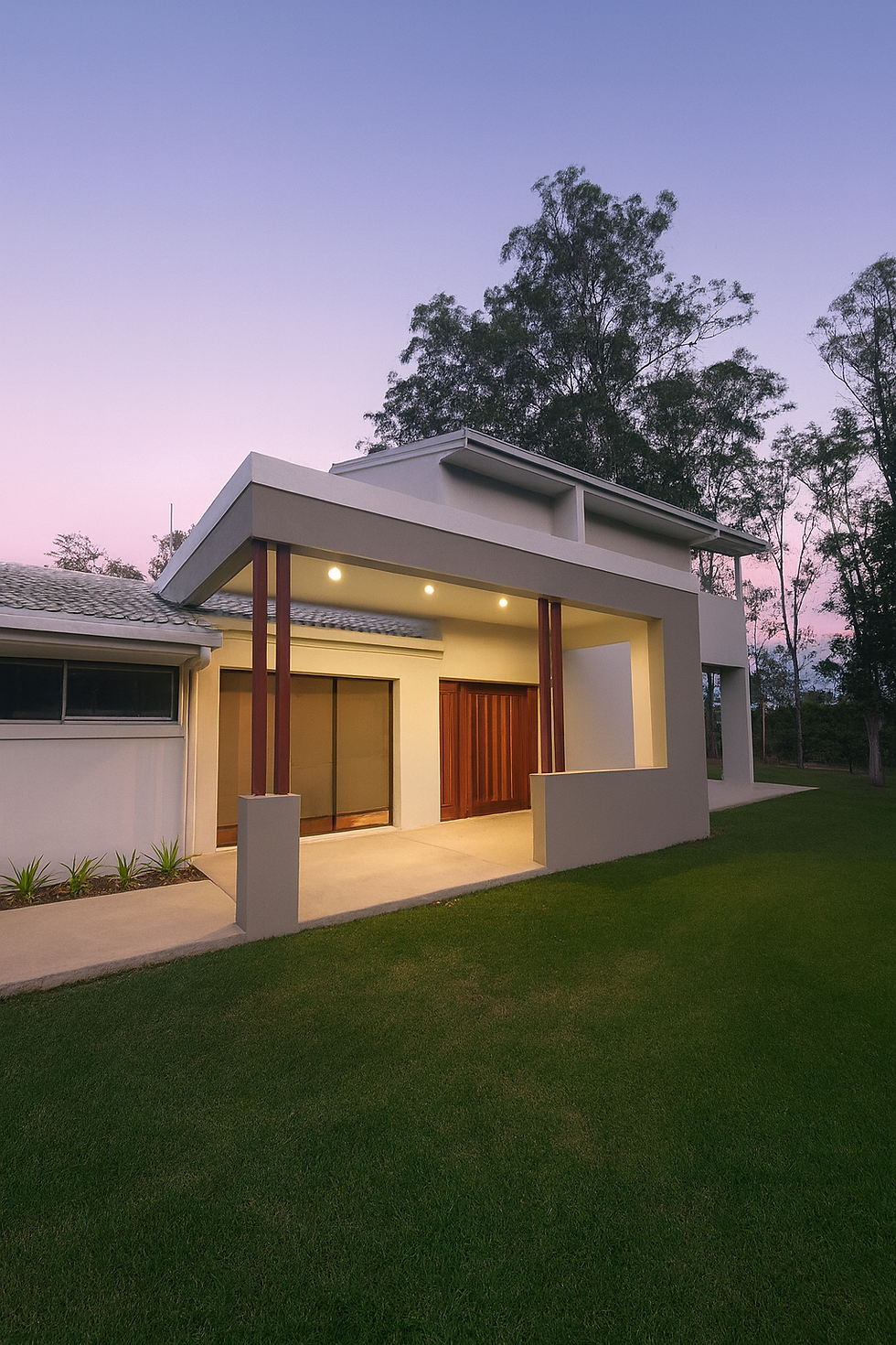 Queensland modern house with wooden door and large windows, show casing the acrylic render, illuminated by warm lights. Surrounded by lush greenery at twilight with a pink sky.