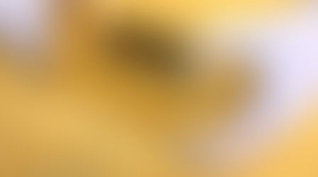 Hands in white gloves hold a shiny gold bar inscribed with 999.9 against a glittering golden background, conveying wealth and luxury.