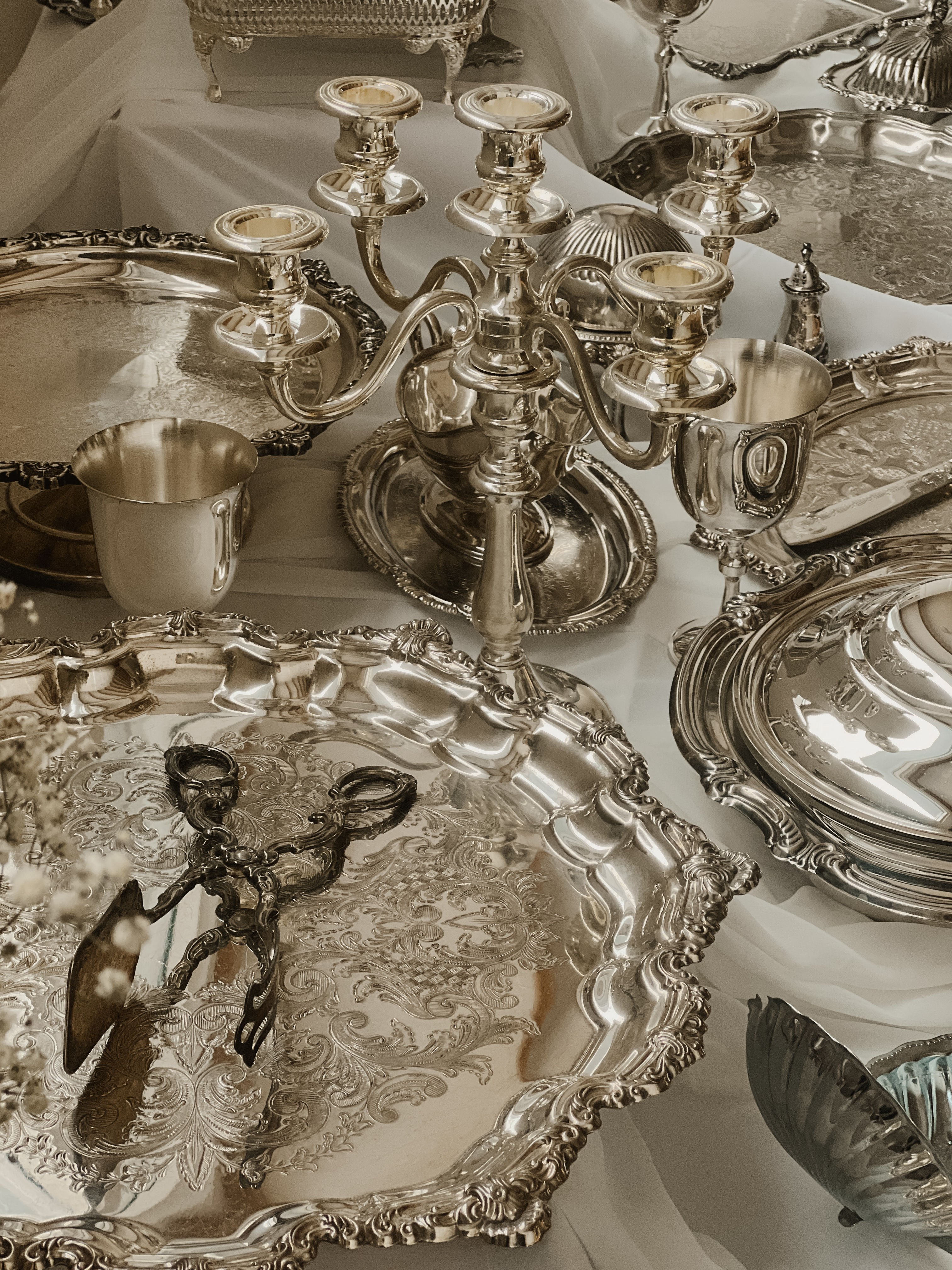 Luxury vintage silverware collection featuring ornate candelabras, engraved trays and serving pieces for wedding and event hire in Melbourne.