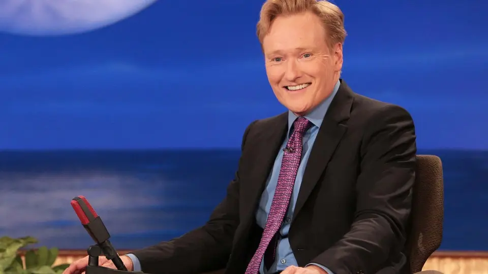 Conan O'Brien sitting behind his desk on the Late Show.