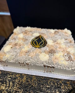 Delicious rectangular cake with white icing and golden aesthetics logo in the center