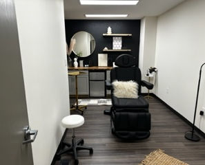 Injection room with black accent wall and black treatment chair