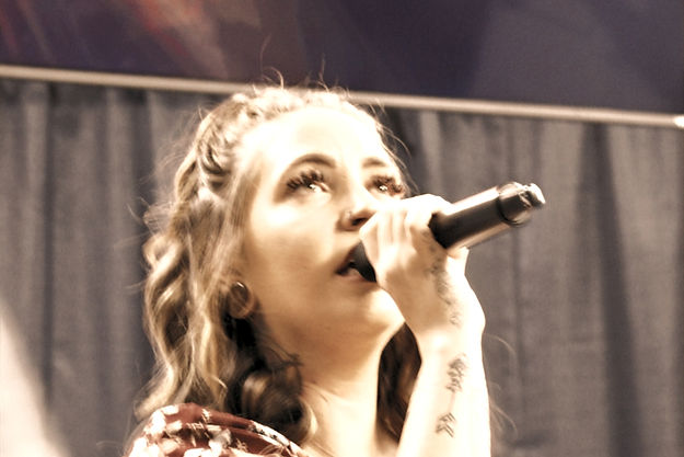 a young women sing with her eyes closed illuminated by spot light 