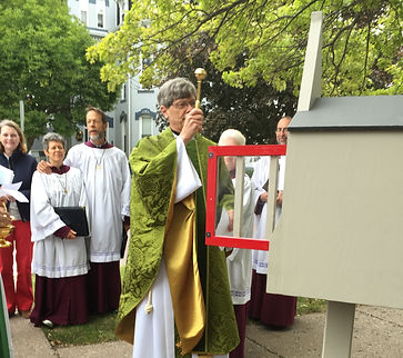 a robed man blesses a little free libray
