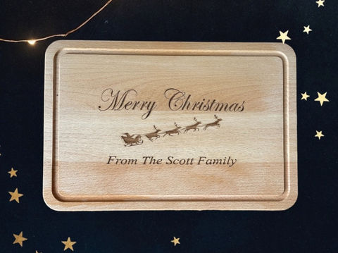 A wooden chopping board engraved by Sweet Pea Laser boutique which reads "Merry Christmas from the scott family"